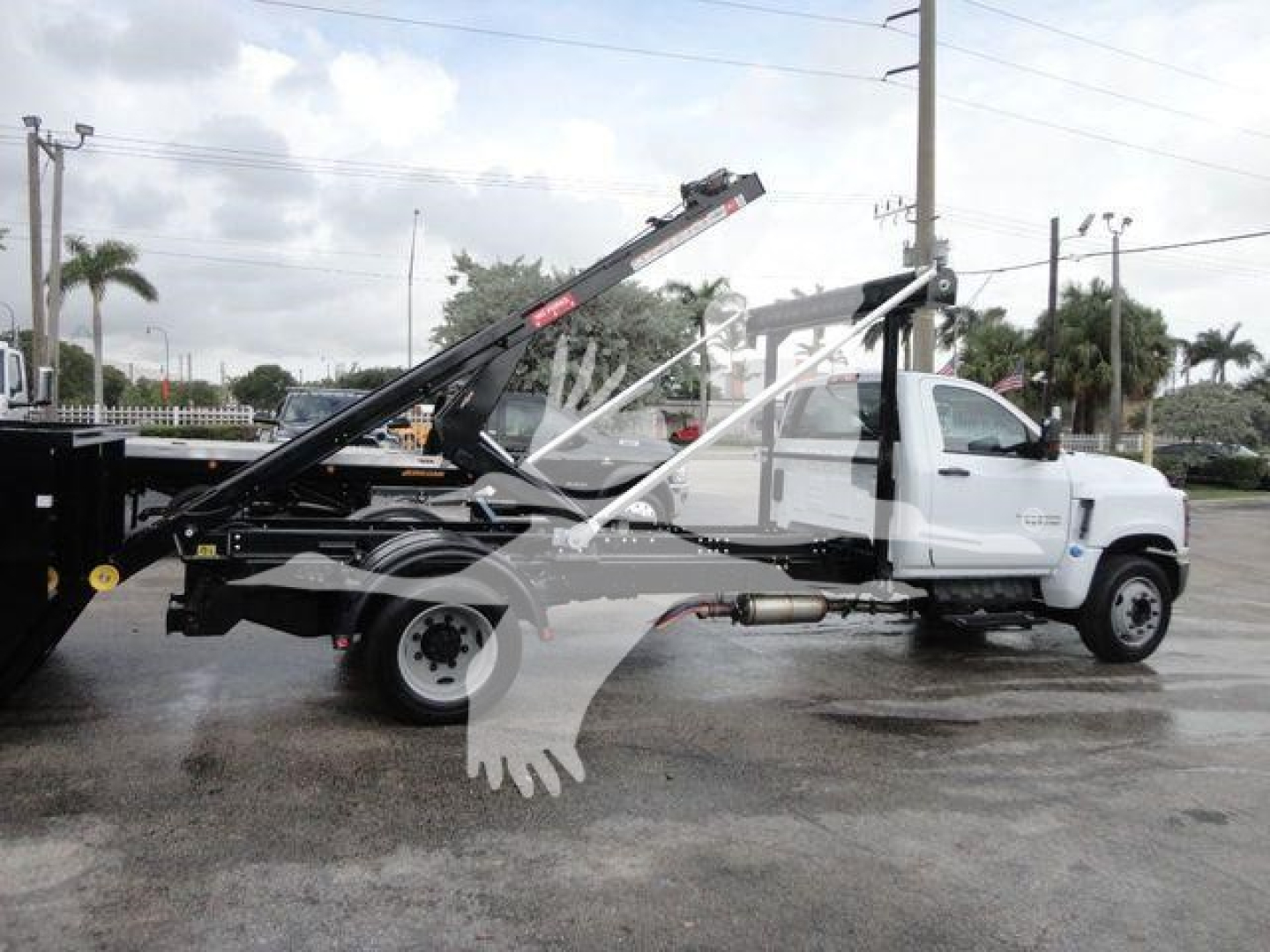 Chevrolet Silverado 5500HD roll-off tow truck side view showing hydraulic tilt bed and winch with white cab and black chassis.