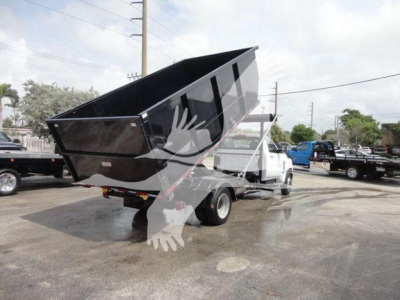 Dump truck bed raised on a white Chevrolet Silverado 5500HD chassis in a dealership lot showing a black dumping bed and rear wheels.