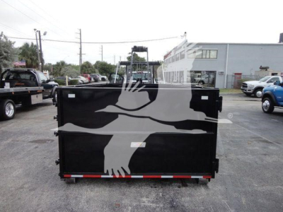 Back of a black dump trailer with a white graphic of a bird in flight on the tailgate; red-and-white reflective strip along the bottom edge; no visible text readable.