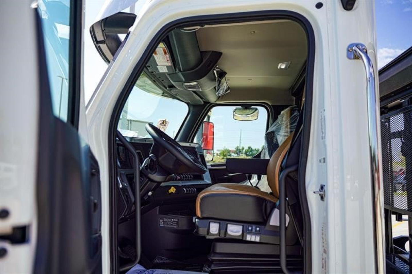 Interior cab view of a new Western Star 47X roll-off truck showing driver seat, steering wheel, and dashboard.