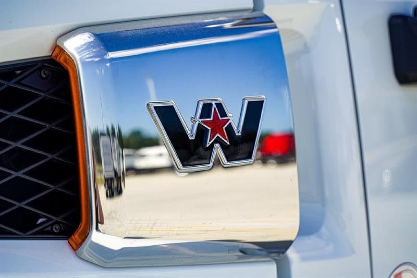 Front grille area of a Western Star truck showing chrome emblem with red star and surrounding blue hood, close-up detail.