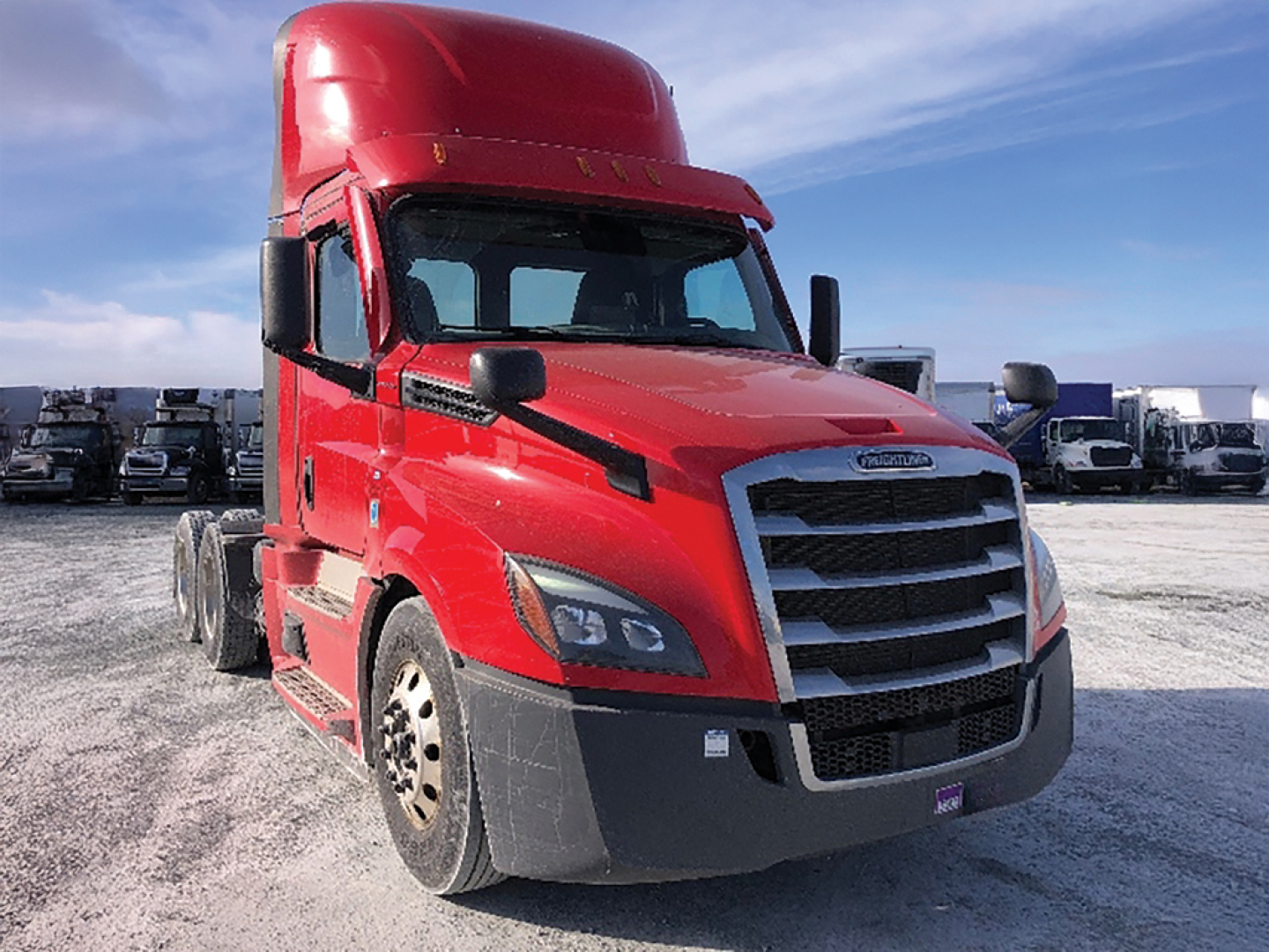 Freightliner Cascadia126 tractor cab showing red exterior and front grille, with multiple trucks in the background.