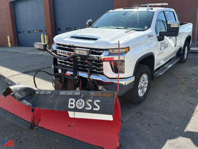 Front angle of a white 2020 Chevrolet Silverado 2500HD Crew Cab with a Boss plow attached, daytime exterior view, dealership stickers on door.
