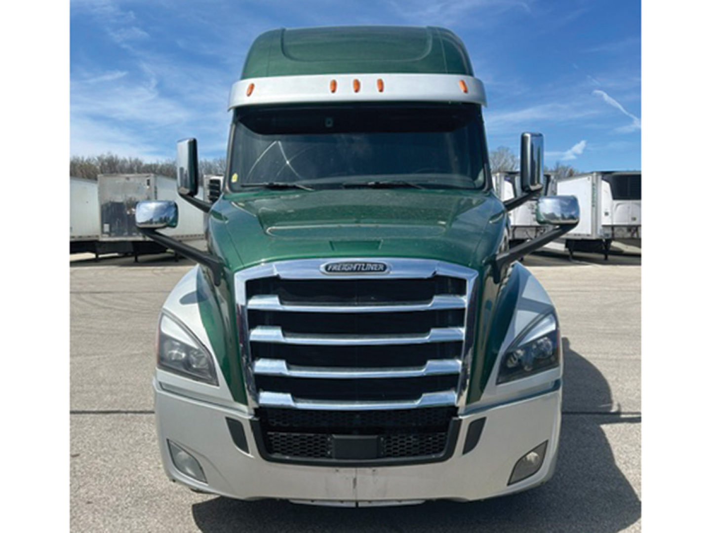 Front view of a green Freightliner Cascadia126 truck with chrome grille and large bumper; no legible warning labels visible.