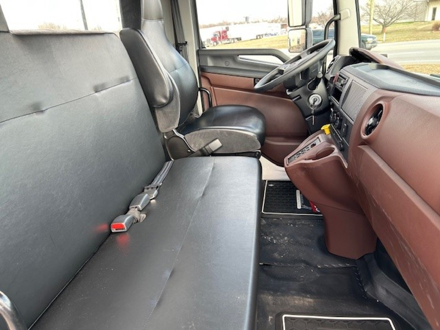 Cab and chassis interior showing front bench seat and dashboard with brown accents and steering wheel on right side of image.