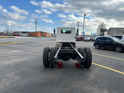 Truck chassis rear view showing dual rear axles and bare frame with hitch, cab in front and open space where cargo body would be mounted.