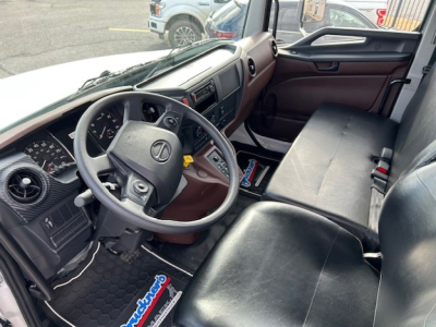 Interior of a 2025 Hino L6 cab and chassis truck showing steering wheel, dashboard, and front bench seat with black upholstery.