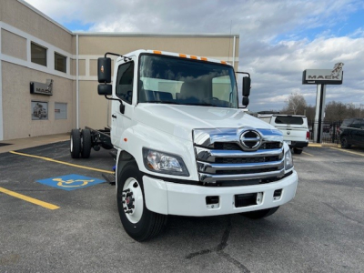 Hino L6 cab and chassis truck in white, front view with chrome grille and bumper, dealership lot in background.