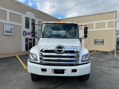 Hino L6 cab and chassis front view showing chrome grille, large Hino emblem, white bumper, and cab in white with amber clearance lights.