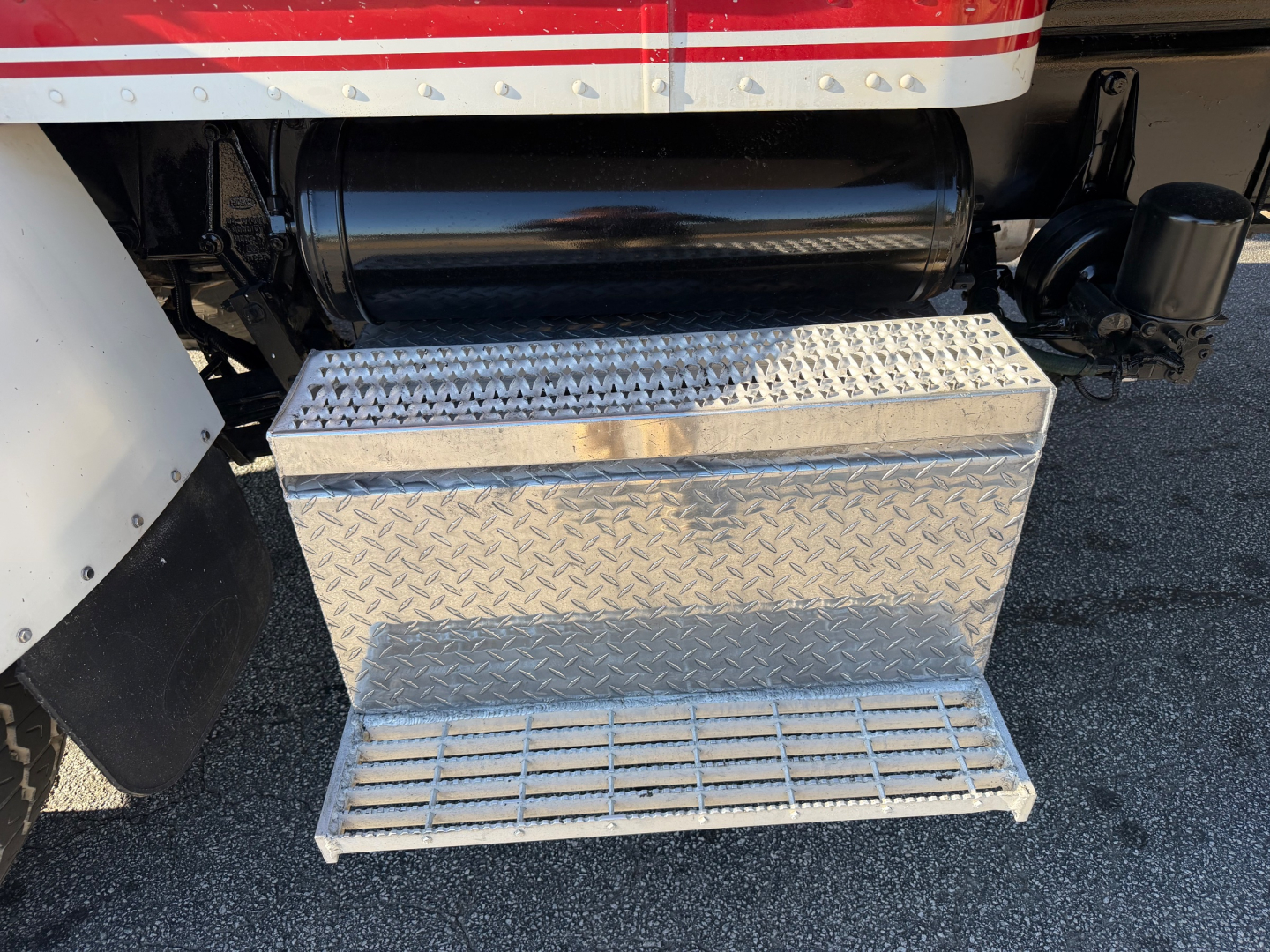 Truck side view showing aluminum diamond plate step/footboard under fuel tank of a 2007 Peterbilt 335 with flatbed configuration