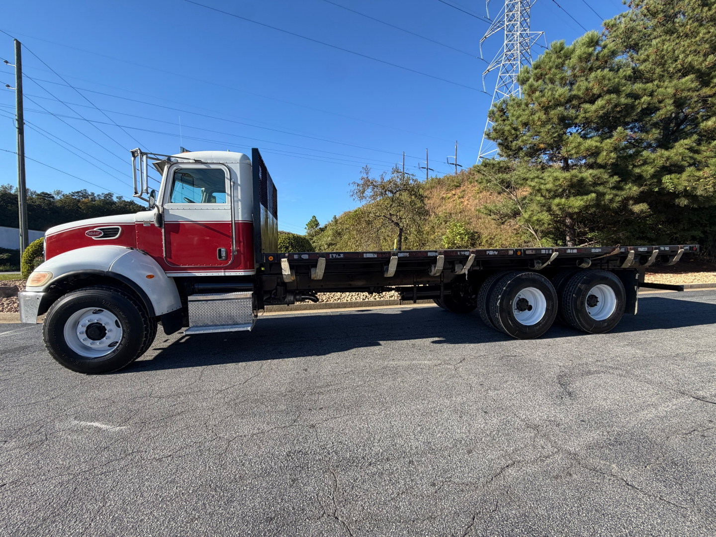 2007 Peterbilt 335 flatbed truck side view showing red cab with chrome bumper and long flatbed chassis.