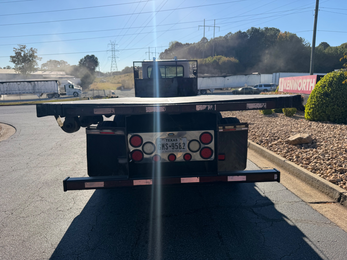 Flatbed tow truck rear showing bumper and license plate area with Texas MS-9582 plate, rear deck edge and taillights.