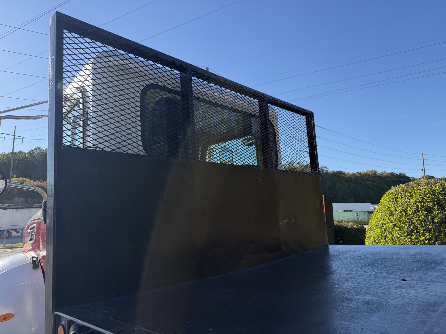 Peterbilt flatbed truck rear view showing metal mesh cab partition, flatbed surface, and partial cab window.