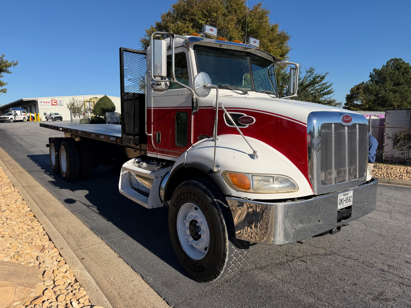 Peterbilt tow truck flatbed with red and white paint showing chrome bumper and grille, front wheel, and flatbed behind cab.