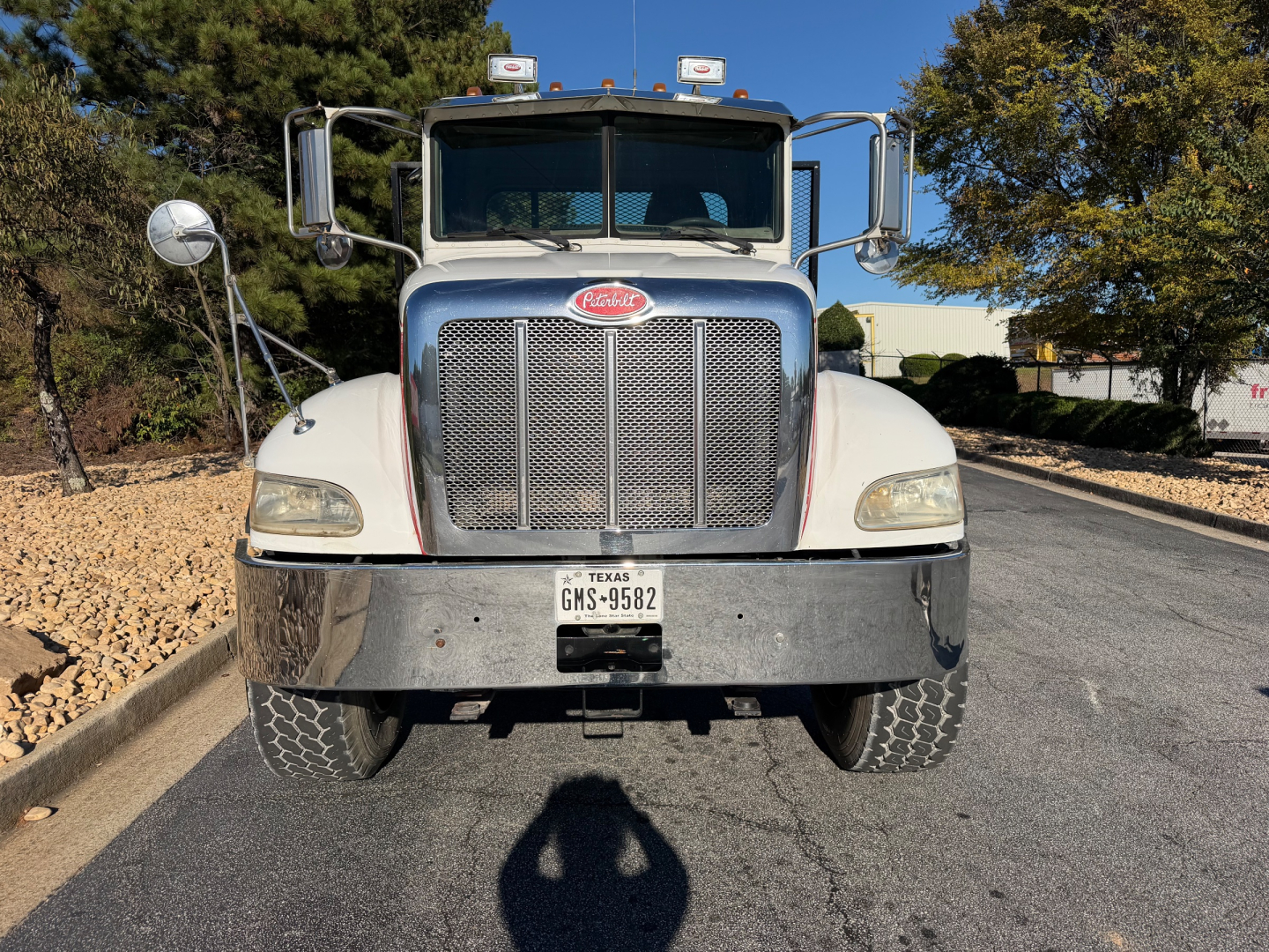 Peterbilt 335 front view showing chrome grille, dual mirrors, large bumper, Texas license plate, flatbed truck in service condition.