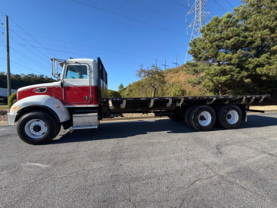 2007 Peterbilt 335 flatbed truck side view showing red cab with chrome bumper and long flatbed chassis.