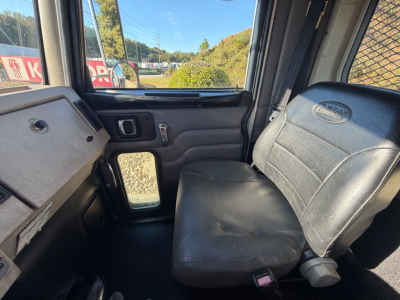 Peterbilt truck cab interior showing driver-side door panel, window, and bench seat with black vinyl upholstery.