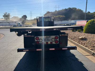Flatbed tow truck rear showing bumper and license plate area with Texas MS-9582 plate, rear deck edge and taillights.