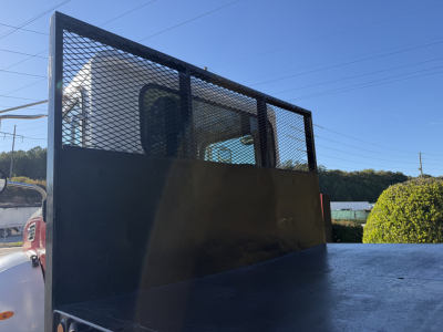 Peterbilt flatbed truck rear view showing metal mesh cab partition, flatbed surface, and partial cab window.