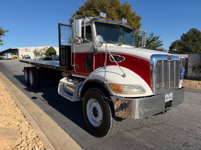 Peterbilt 335 flatbed truck in-service showing front grille, dual mirrors, chrome bumper, white and red cab, and flatbed chassis.