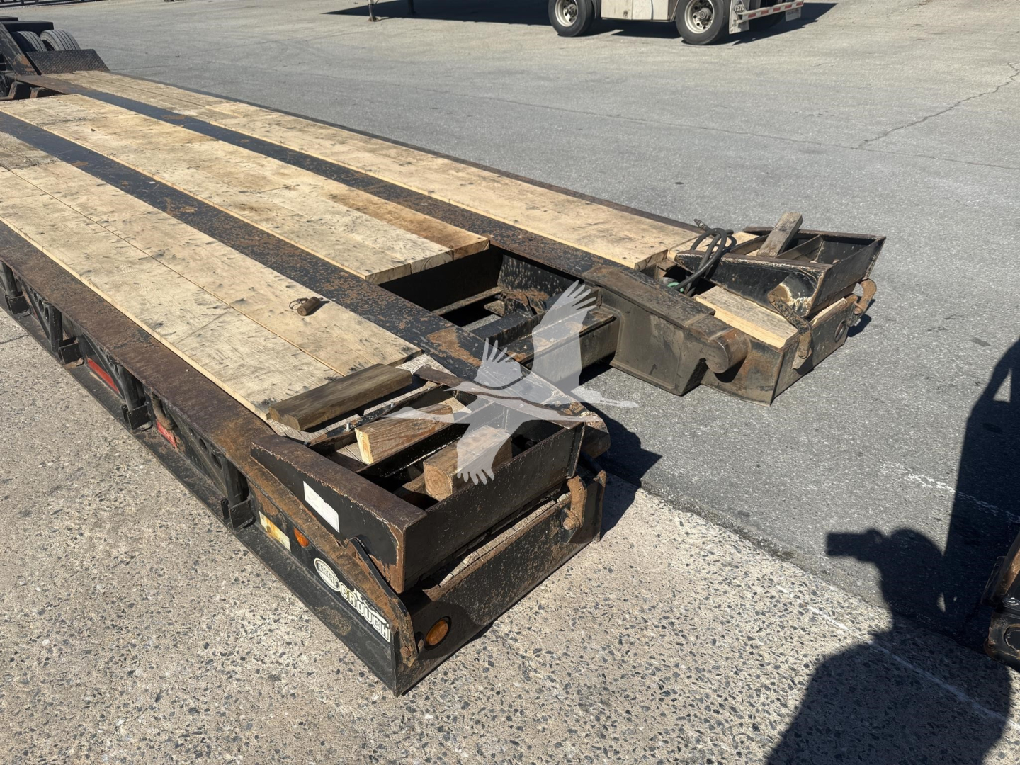 Trailer deck showing wooden planks and metal frame of a 50-ton lowboy trailer portion with ramps folded up.