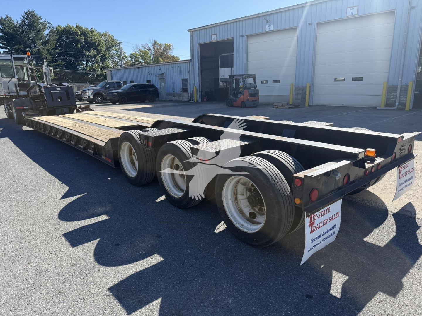Trailer showing a 50-ton lowboy with three axles and dual wheels, Rogers 50-ton, with signage on rear, VIN 1RBH503023AR24223 along with stock number 7613.