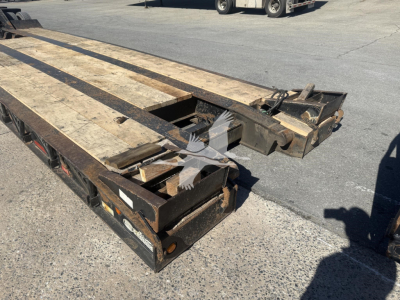 Trailer deck showing wooden planks and metal frame of a 50-ton lowboy trailer portion with ramps folded up.