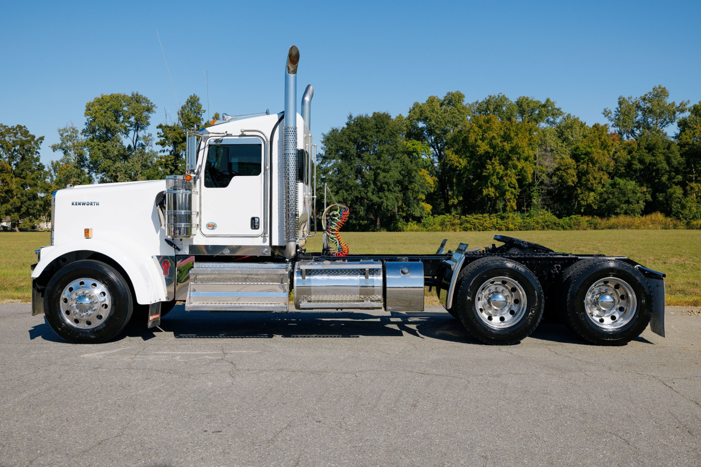 Kenworth W900L conventional sleeper truck left-side view showing chrome fuel tanks and dual rear axles.