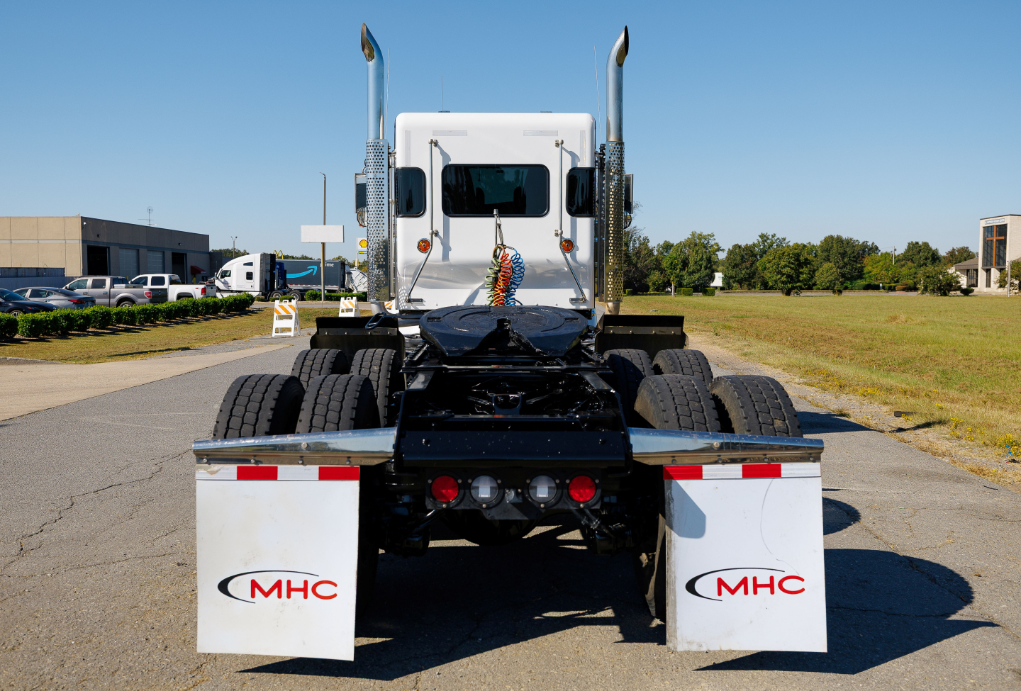 Kenworth W900L rear view showing dual rear axles and white mud flaps with MHC logos