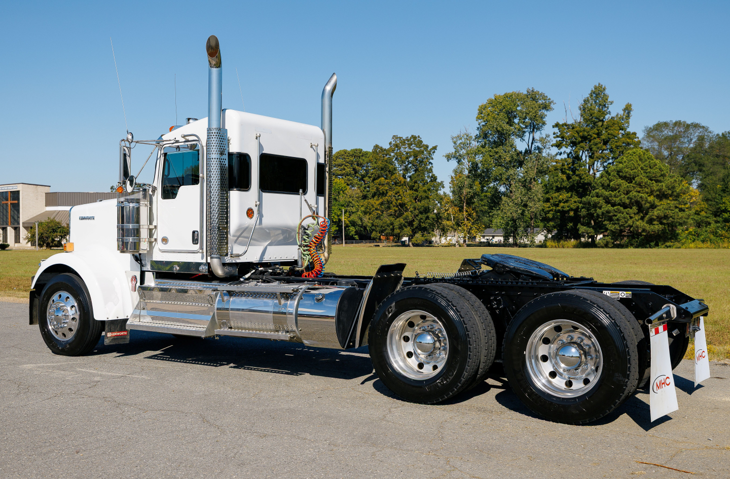 Kenworth W900L tractor in side profile showing chrome fuel tanks, dual rear axles, and sleeper cab.