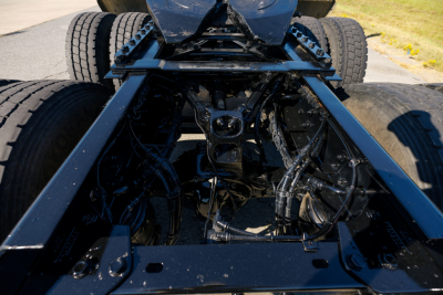 Kenworth W900L chassis and drivetrain view showing underside frame rails and wiring.