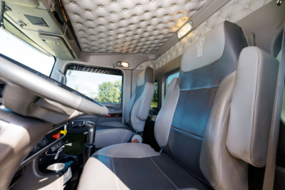 Kenworth W900L interior cab view showing leather seats and quilted headliner with steering wheel and dashboard.