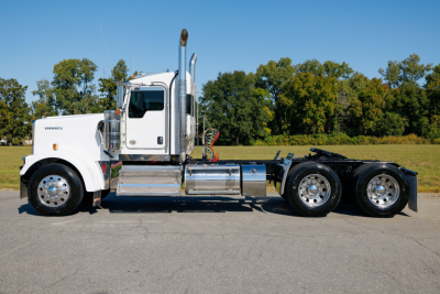 Kenworth W900L conventional sleeper truck left-side view showing chrome fuel tanks and dual rear axles.