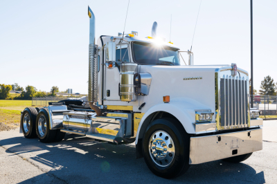 Kenworth W900L conventional sleeper truck with white cab and chrome accents, front grille and bumper, dual rear axles, text 'KENWORTH' on grille