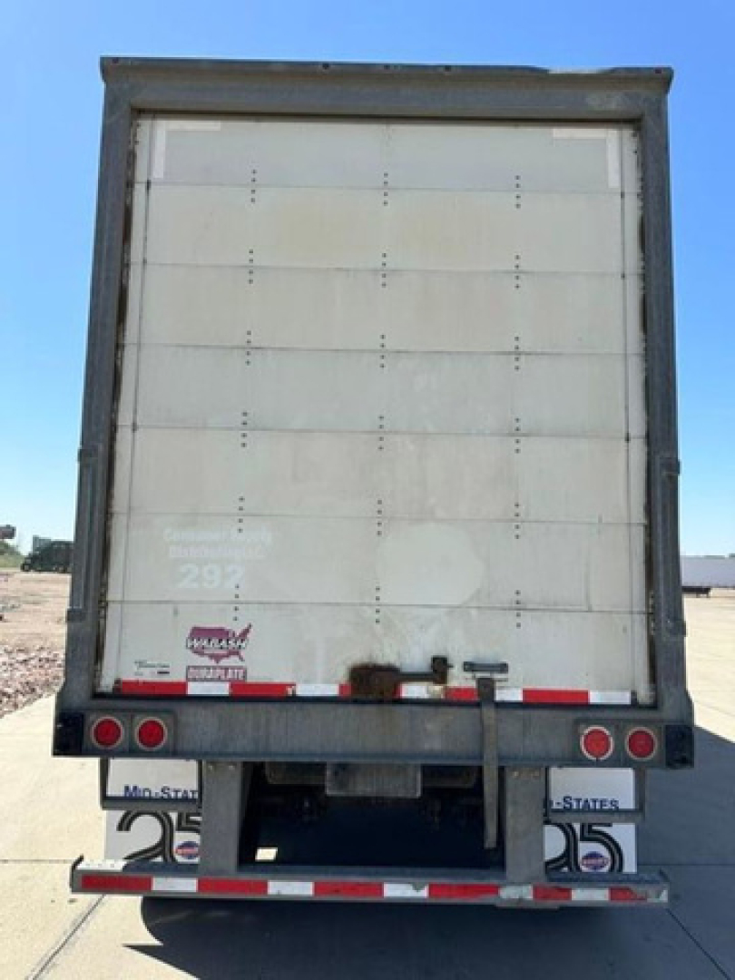 Rear view of a 2016 Wabash van trailer showing back doors, taillights, bumper, and mud flaps with registration numbers.