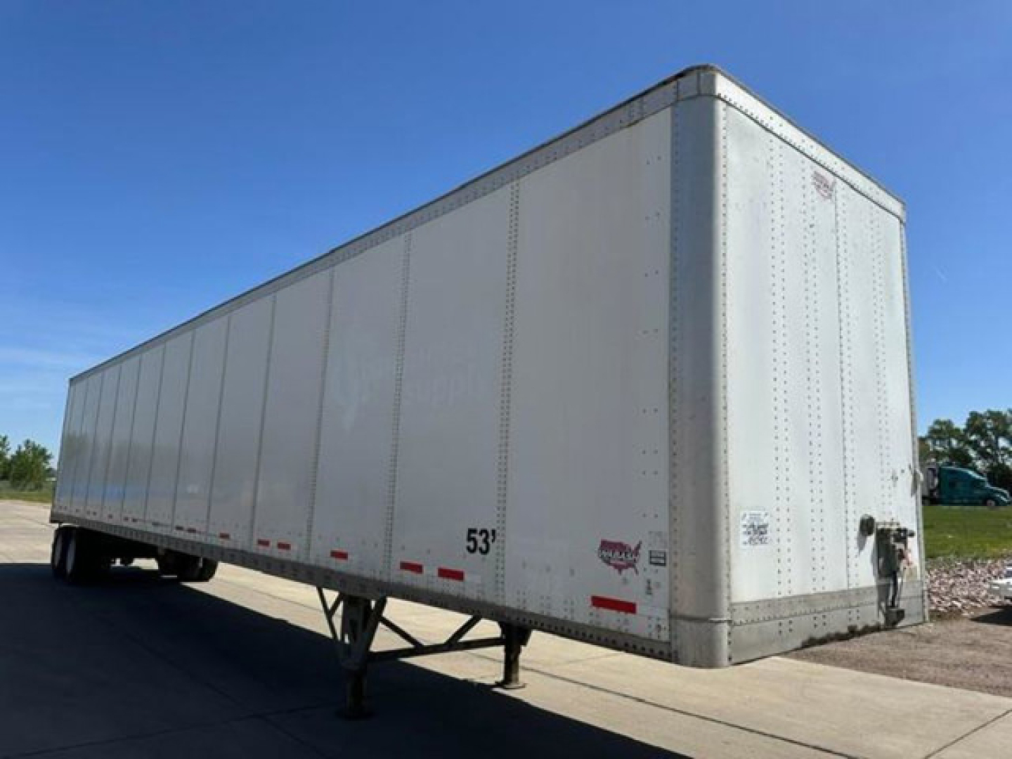 Trailer in-service showing side and front with 53' length marking and rear door hardware. There are small decals and a hitch visible on the front corner.
