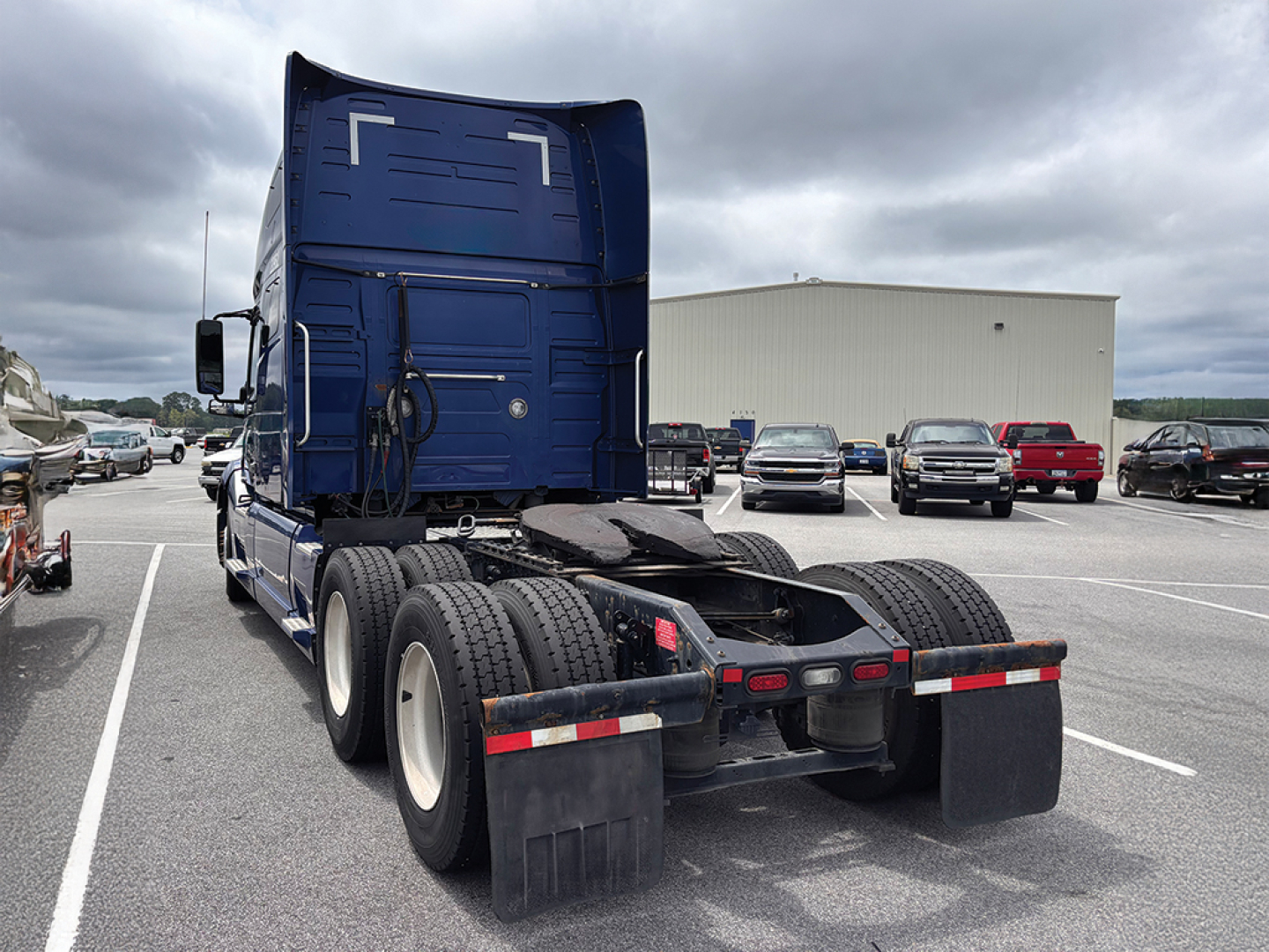 Rear view of a 2022 Volvo VNL 760 tractor in a used truck lot showing dual rear axles, fifth wheel, and mud flaps.