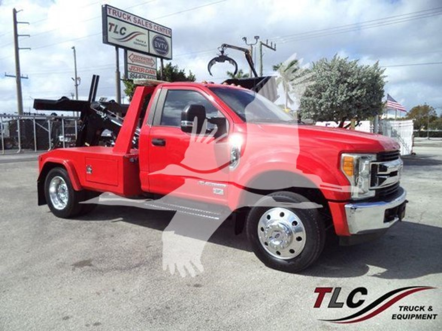 Ford F-450 tow truck with utility bed and mounted winch, red exterior, chrome front bumper, daytime outdoor lot.