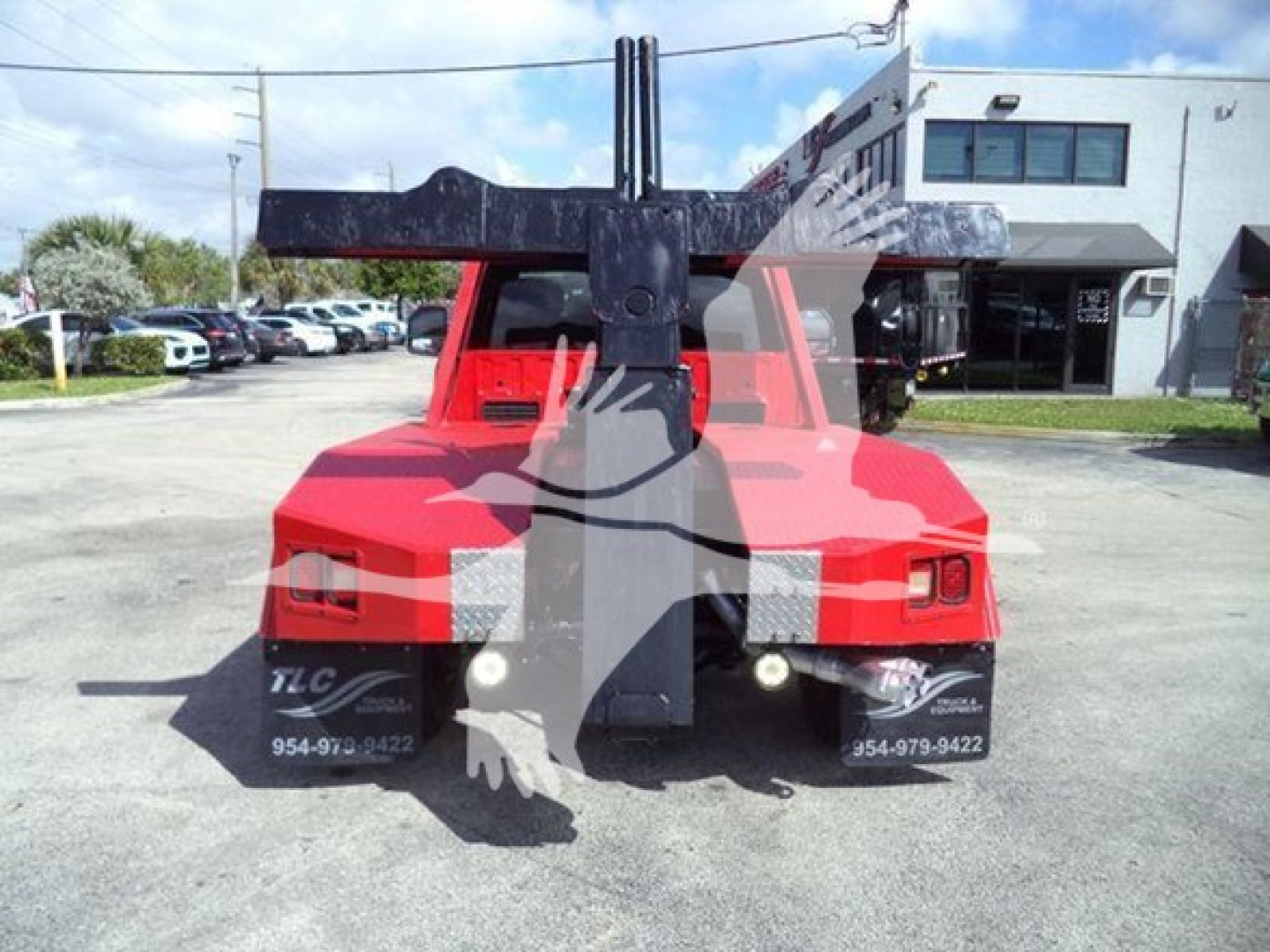 Truck rear view showing a winch/loader crane on a red Ford F-450 with large steel arms and hooks visible.