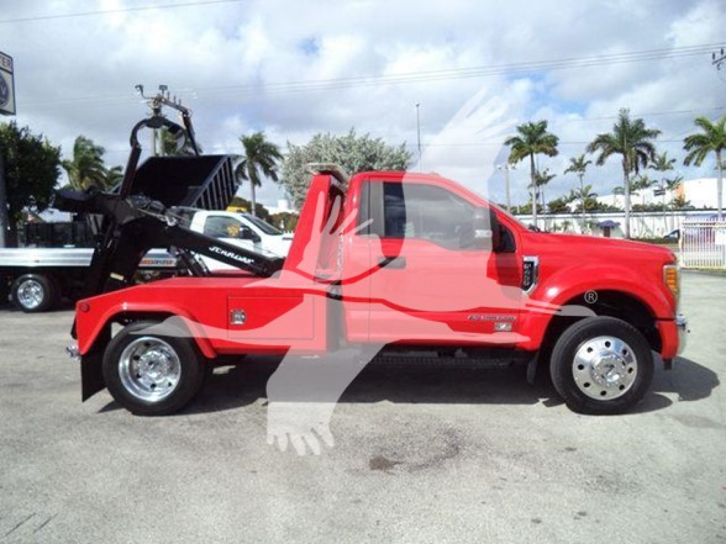 Ford F-450 tow truck side view showing winch equipment and red cab with black tow body