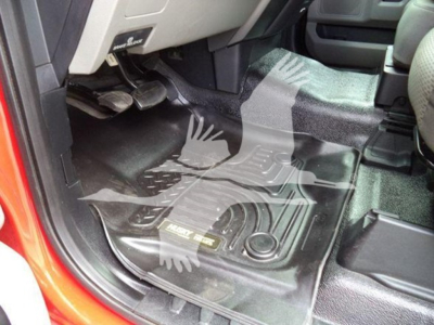 Ford F-450 interior driver footwell with floor mat and pedal area; visible floor console and a storage hatch near the driver’s seat; some text on a plate near the floor mat