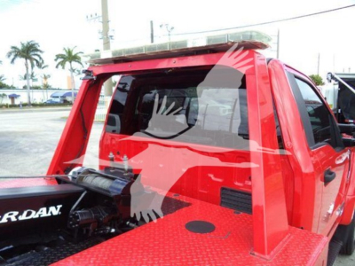 Truck bed area of a red Ford F-450 with winch setup and bolt-on rack, showing side panel and exposed winch motor.