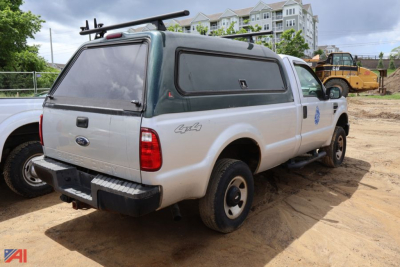 Ford F-250 Super Duty pickup with green camper shell and rear ladder rack, cargo area, rear view showing taillights and bumper