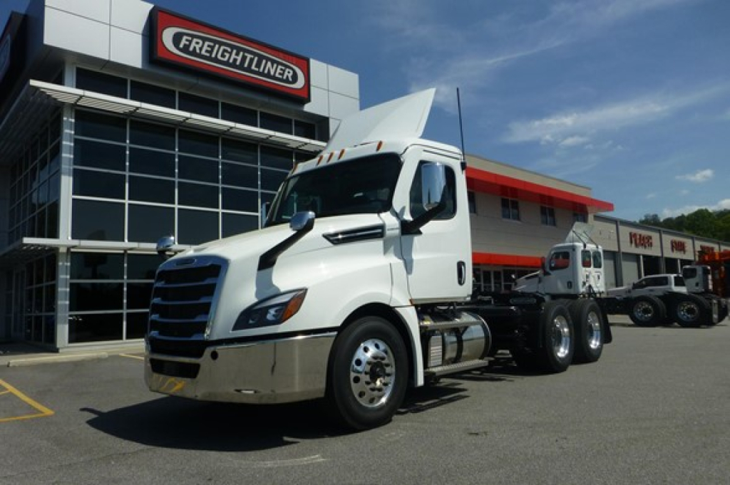 Freightliner Cascadia 126 day cab truck in front of dealership with white cab and sleeper raised hood