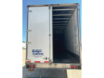 Rear view of a utility trailer with rear doors open showing the empty cargo area, Badger Express logo on left door, aluminum frame, taillights and bumper.