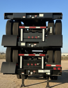 intermodal chassis trailer rear view showing dual axles and multiple battery/equipment boxes with red reflectors and black metal frame