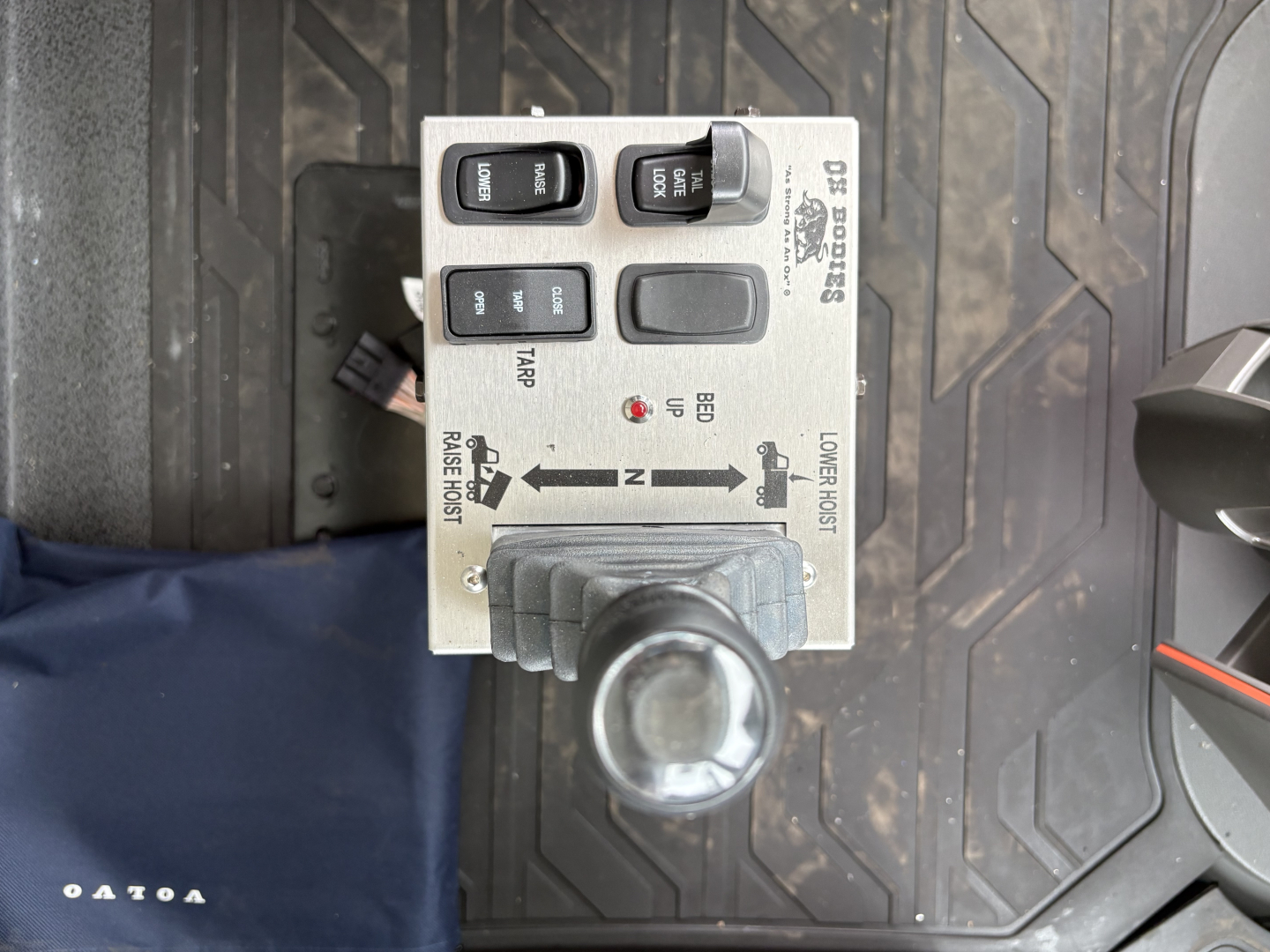 Dashboard control panel with levers and switches labeled low/high range, ‘REVERSE/FRONT’ indicators, and a grey joystick in a Volvo dump truck cab.