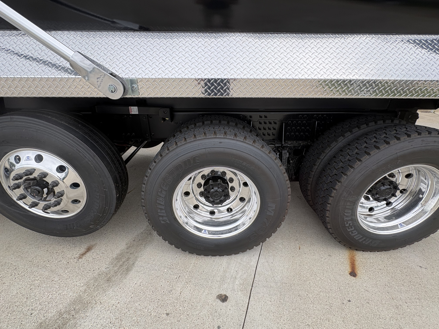 Triple rear axle section of a Volvo VHD truck showing dual rear tires and chrome rims with polished wheel hubs.