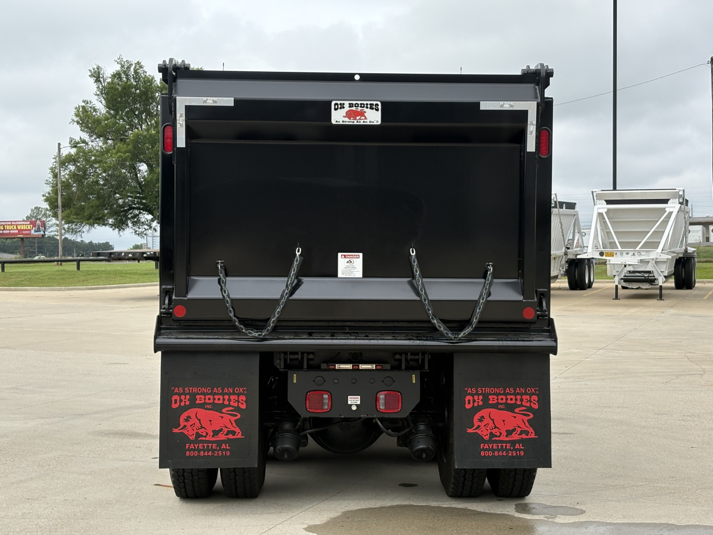 Volvo VHD84F300 dump truck rear view showing empty dump bed and mud flaps with red graphics.