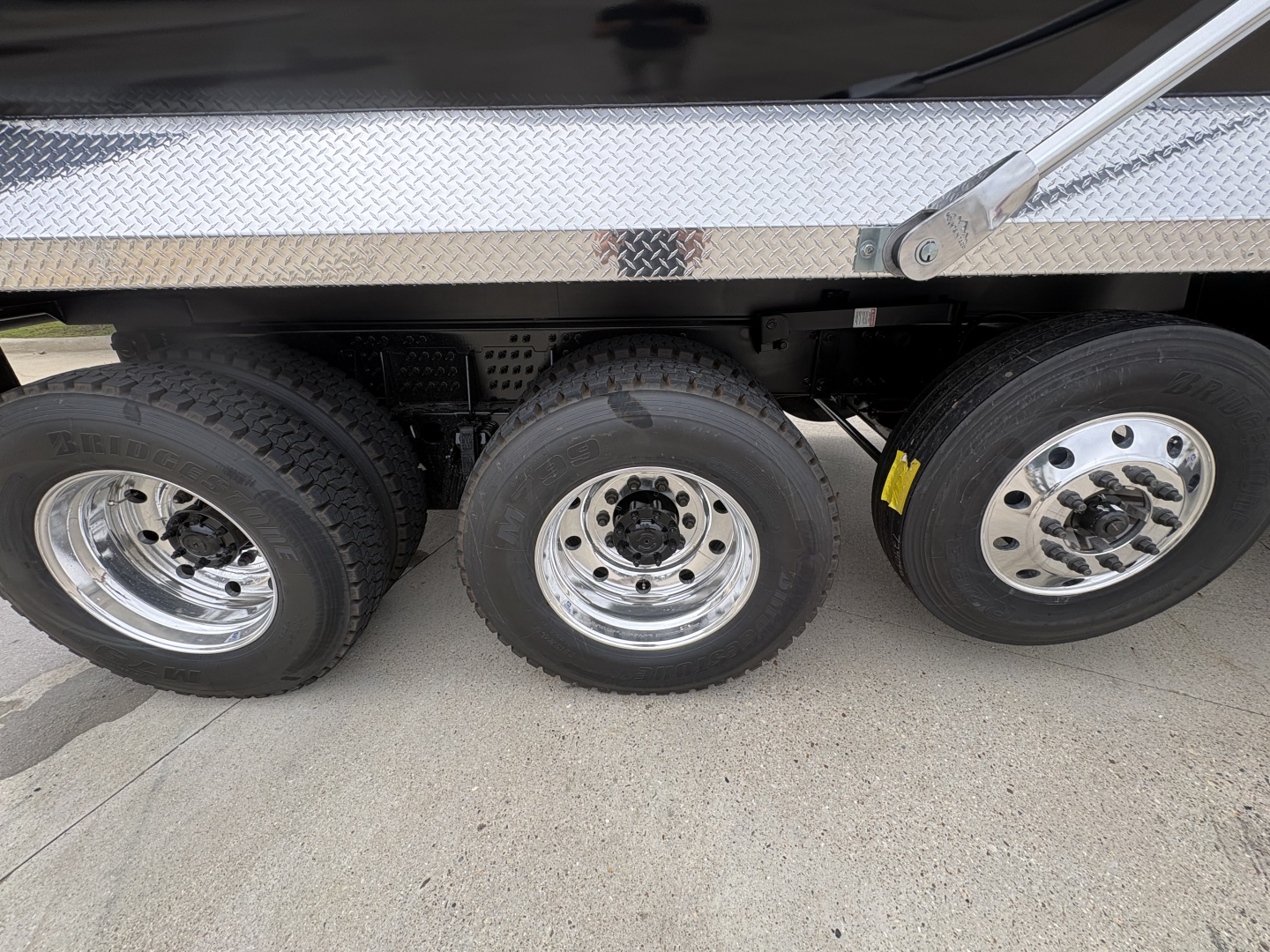 Side view of a Volvo VHD84F300 dump truck showing triple rear axles with shiny chrome wheels and diamond plate side panels.